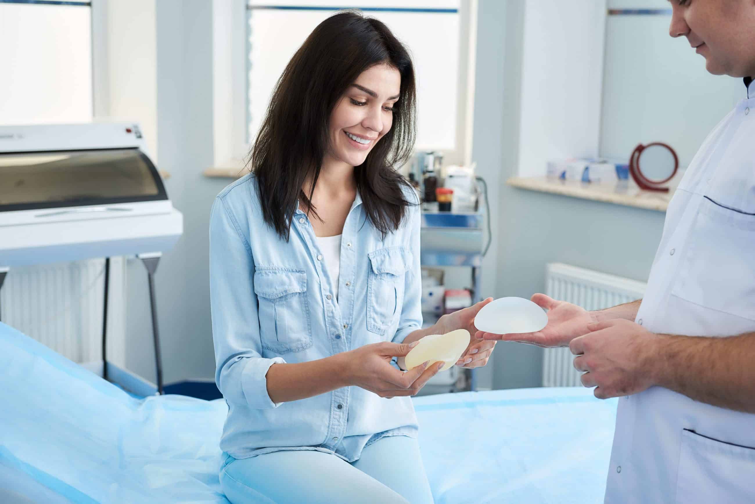 woman holding Saline and Silicone breast implants